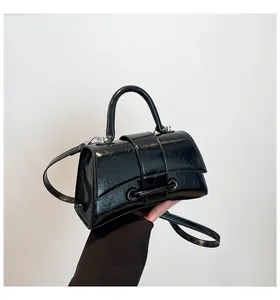 Detailed view of the black hourglass crossbody bag with curved base and shiny cracked leather