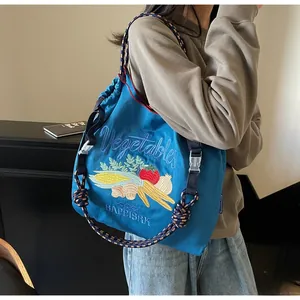 Détail de broderie de légumes colorés sur un sac à provisions bleu en nylon avec cordon