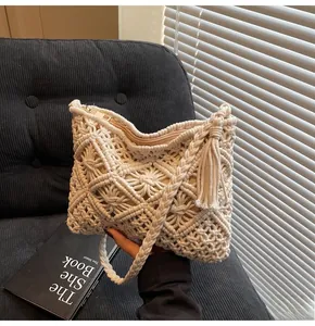 Close-up of cream knit bucket bag showing intricate hollow weave patterns and tassel detail