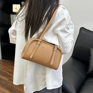 Elegante borsa a spalla baguette color cammello indossata da modella in uno studio