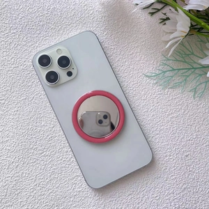 Detail of pink magnetic MagSafe makeup mirror and phone socket on white smartphone