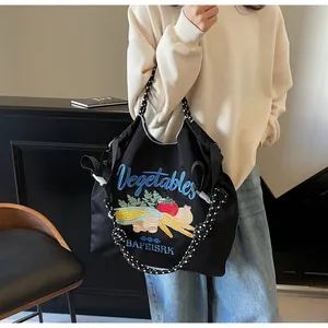 Détail d'un grand sac fourre-tout noir brodé de légumes avec anses à pois élégantes