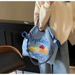 Gros plan sur le sac fourre-tout en nylon bleu clair avec broderie de légumes colorée