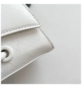 Close-up of white leather handbag showing wrinkled texture and detailed stitching