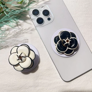 Detailed top view of camellia flower phone grips in black and white on textured fabric