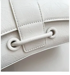 Detailed close-up of white wrinkled leather texture and metal eyelets on the bag