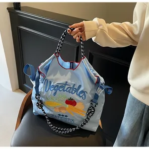 Détail de broderie de légumes sur sac en nylon bleu clair avec anses rayées