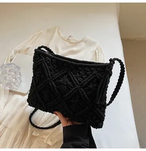 Detail of black woven bucket bag with geometric patterns and tassel strap