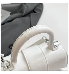 Detail of white hourglass handbag with glossy pleated texture and silver metal hardware