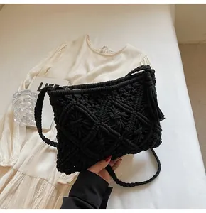 Close-up of black hollow knit bucket bag featuring handcrafted diamond texture and tassels