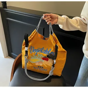 Détail du sac cabas jaune en nylon avec broderie légumes et bandoulière à damier