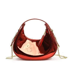 Detail of red patent leather crescent bag with golden chain and glossy mirror finish