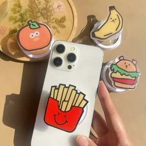 Cute acrylic phone grips in fruit shapes like banana and fries on a white mobile phone