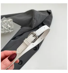 Detailed view of white crocodile pattern slim leather belt with silver pin buckle buckle