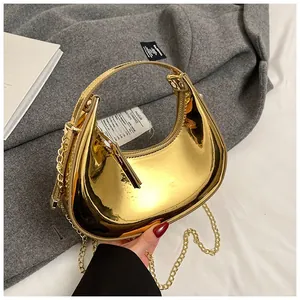 Close-up of golden metallic crescent bag with chain strap and reflective mirror finish