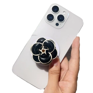 Hand holding phone with black and white camellia flower socket grip and golden center