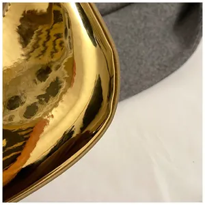 Macro shot showing the gold mirror finish and curved edges of the glossy patent handbag