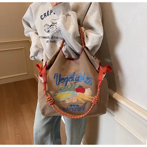 Détail du sac hobo avec broderie de légumes colorés et bandoulière en corde tressée