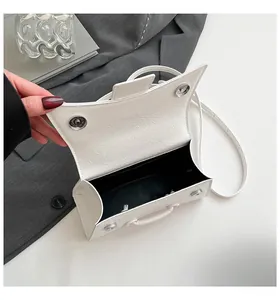 Detail of white textured hourglass bag with metallic magnetic closure and black lining