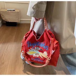 Gros plan du sac cabas rouge en toile avec broderie de légumes et poignées tressées