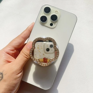Detail of flower-shaped phone grip mirror with crystals and gold metal finish