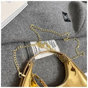 Close-up of golden crescent moon bag with glossy patent leather and gold chain strap