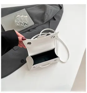 Detail of open cream white hourglass bag showing black lining and silver magnetic buckle