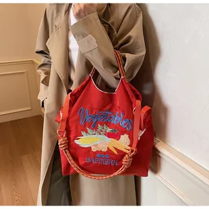 Détail du sac fourre-tout rouge en toile avec broderies légumes et anses tressées