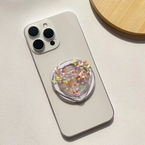 Close-up of a clear round phone socket grip with colorful heart sequins and glitter