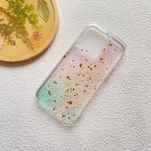 Detail of gradient phone case with gold foil flakes on white textured background