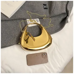 Close-up of golden mirror finish hobo bag with sleek metal handle and chain strap detail