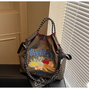 Détail d'un sac cabas en nylon marron avec broderies de légumes et poignées en corde tressée