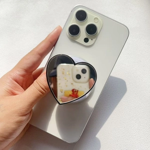 Detail of heart-shaped mirror phone grip stand showing reflective surface on a white phone