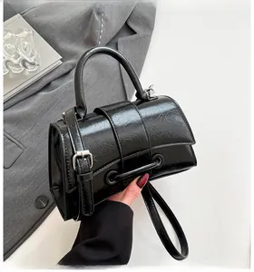 Close-up of black crinkled leather handbag with silver hardware and top handle detail