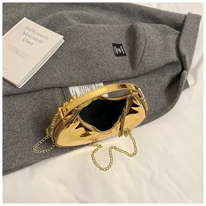 Detailed top view of gold mirror finish crescent bag with metallic chain and black lining