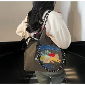 Détail de la broderie de légumes colorés sur un sac fourre-tout en nylon marron durable