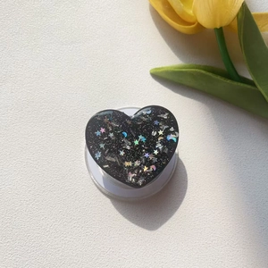 Detail view of heart-shaped magnetic phone grip with glitter and laser star patterns