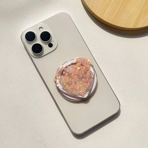 Macro view of heart-shaped glitter phone grip with pink sequins on a white smartphone