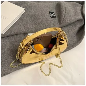 Detail view of gold crescent handbag showing capacity for phone and cosmetics
