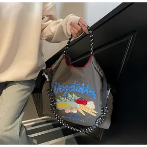 Gros plan détaillé du sac fourre-tout gris avec broderie légumes et bandoulière en corde