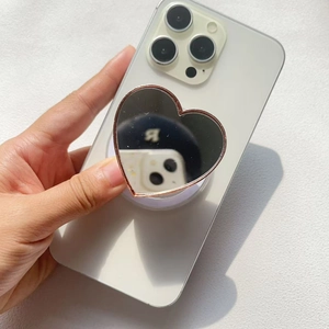 Detail of heart-shaped makeup mirror phone socket with rose gold edges on a white smartphone