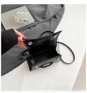 Detail of black glossy hourglass bag with silver magnetic clasp and single compartment
