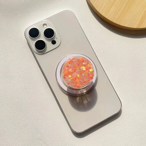 Macro detail of round phone grip with red heart sequins and glitter on white phone back