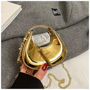 Macro detail of mini gold patent crescent bag with metallic finish and chain strap