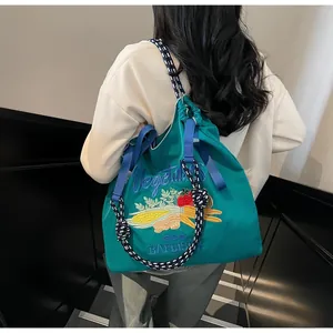 Détail du sac en toile bleu sarcelle avec broderies de légumes et cordes tressées