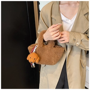Detail of plush brown teddy tote bag with a cute puppy pendant and striped ribbon