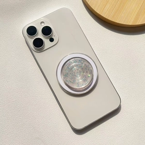 Close-up of heart-shaped phone grip with colorful star sequins on a white smartphone