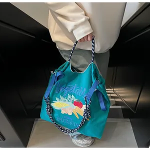 Détail du sac cabas bleu canard avec broderie de légumes et poignées tressées