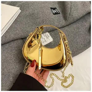 Close-up of golden crescent mini bag with mirror finish and elegant metal chain strap