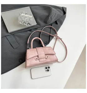 Detailed view of pink hourglass handbag with textured finish and smartphone for scale